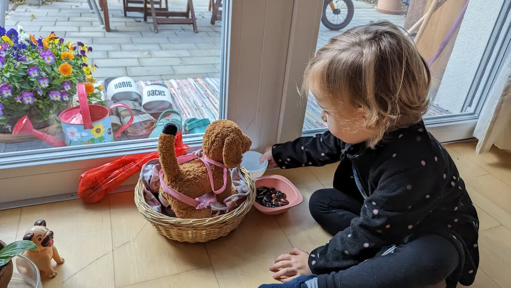 My daughter sitting on the floor feeding her plush dog invisible food.