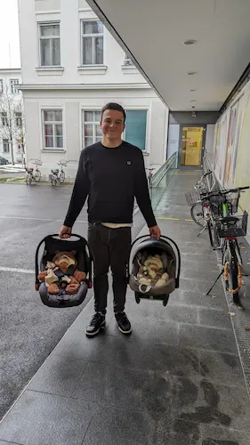 Me holding both babies in baby car seats ready to go home